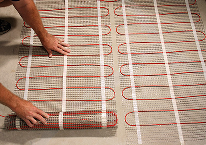 Laying out ComfortTile floor heating mats for heated bathroom floor.